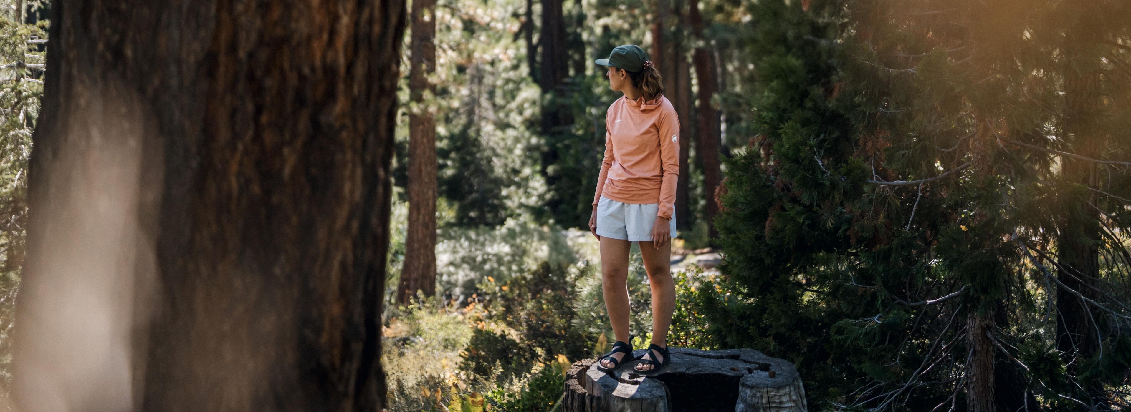 Shop our favorite spring styles featuring a women on a tree stump in the woods wearing the Rogue sandal.