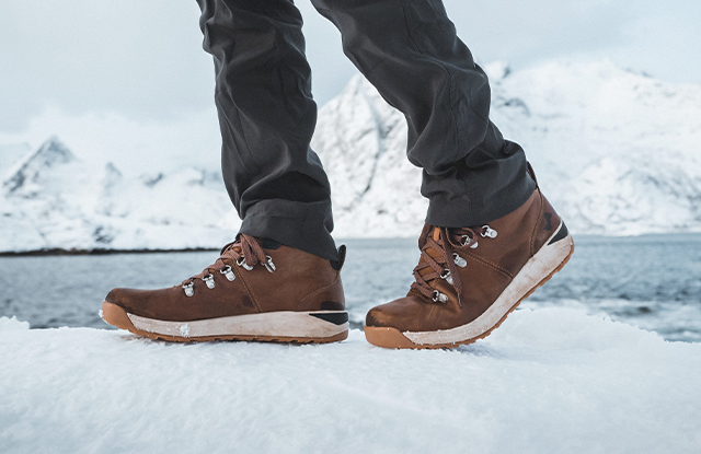 Shoes that have been tried and tested, shop the Halden Mid collection. The image features a person standing in snow, wearing the Halden Mid Waterproof Sneaker Boot in Tan Multi.